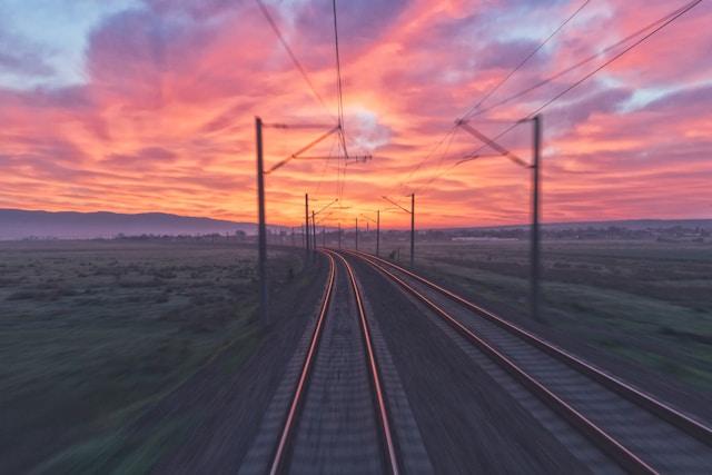 Train tracks stretching into the distance at sunset with a dramatic sky.