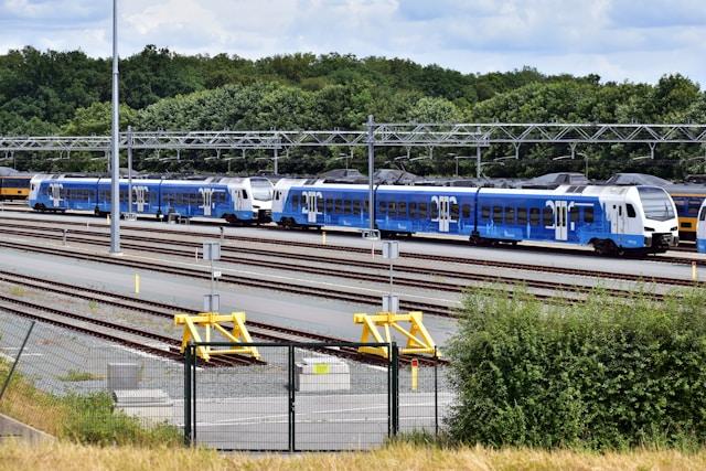 Multiple blue commuter trains at a modern rail yard with electrified infrastructure.