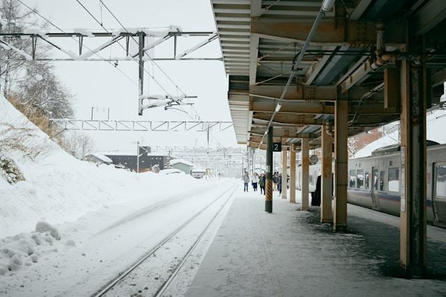 A snow-covered train station platform with trains arriving, showcasing clean winter rail operations.