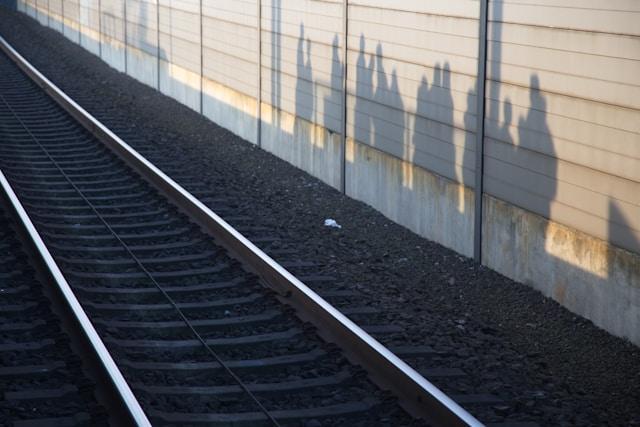 Train tracks with shadows of people on a platform wall, symbolizing community engagement.